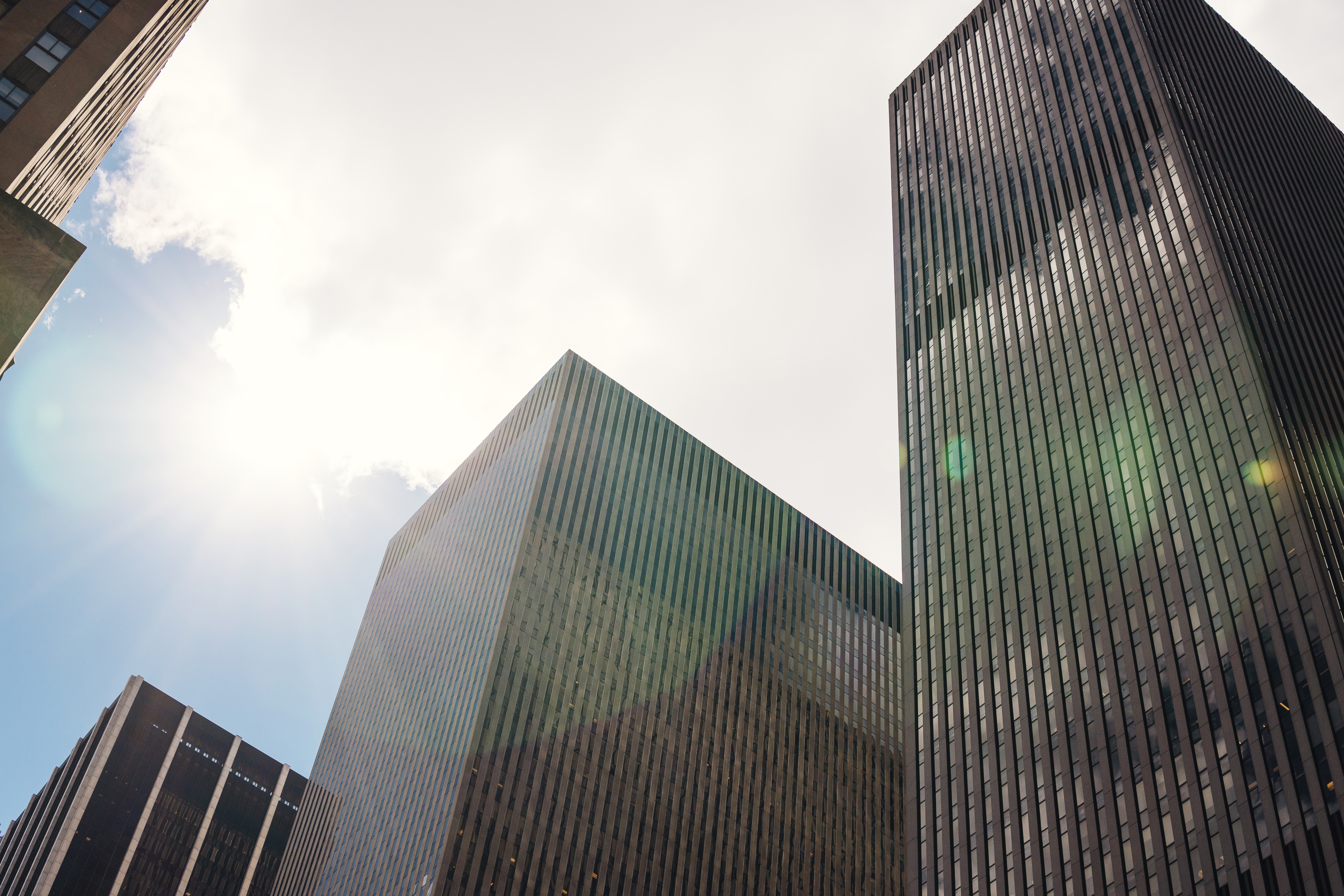Modern skyscrapers reaching towards blue sky with clouds